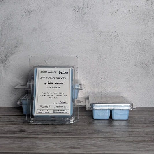 Wax melts with a label on a wooden surface against a gray wall.