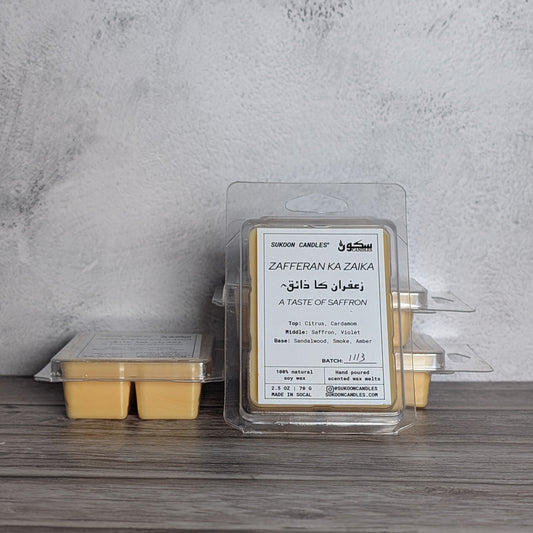 Packaged candle wax melts with a label on a wooden surface against a gray wall.